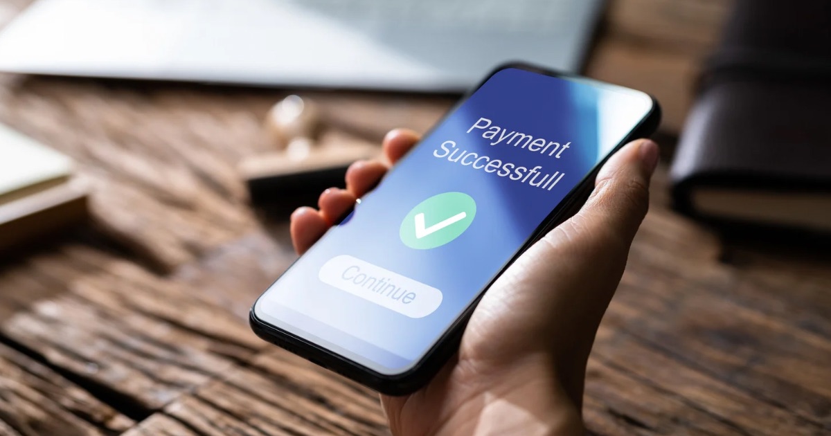 A person holding a smartphone showing “Payment Successful” with a green check mark, representing successful digital money transfers.