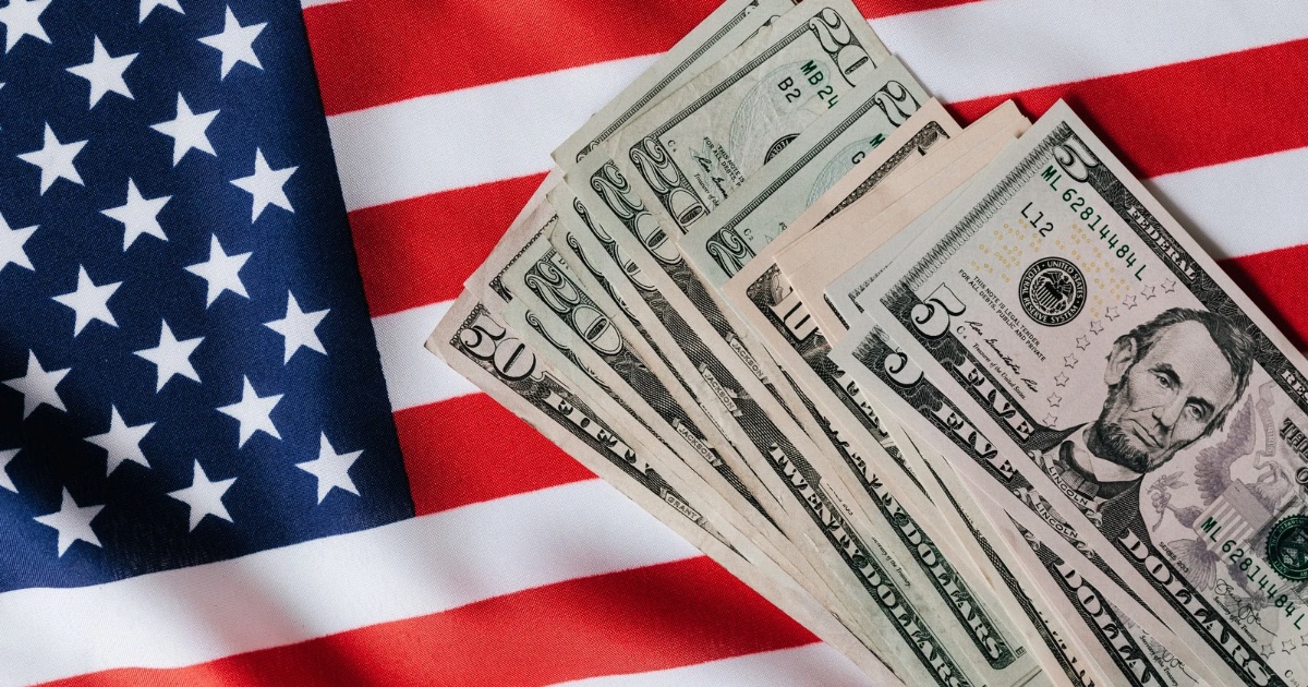 Stack of US dollar bills placed on top of an American flag