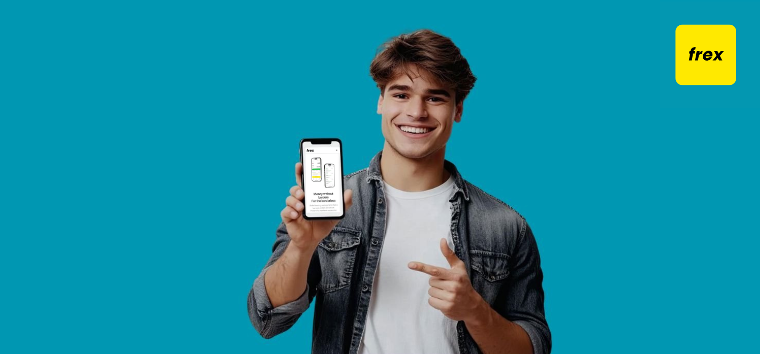 Smiling young man pointing at smart phone and looking at camera