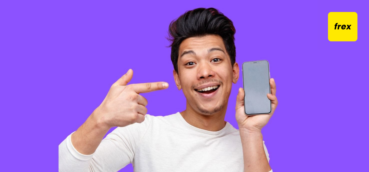 Close-up view of excited young man holding and pointing at mobile phone